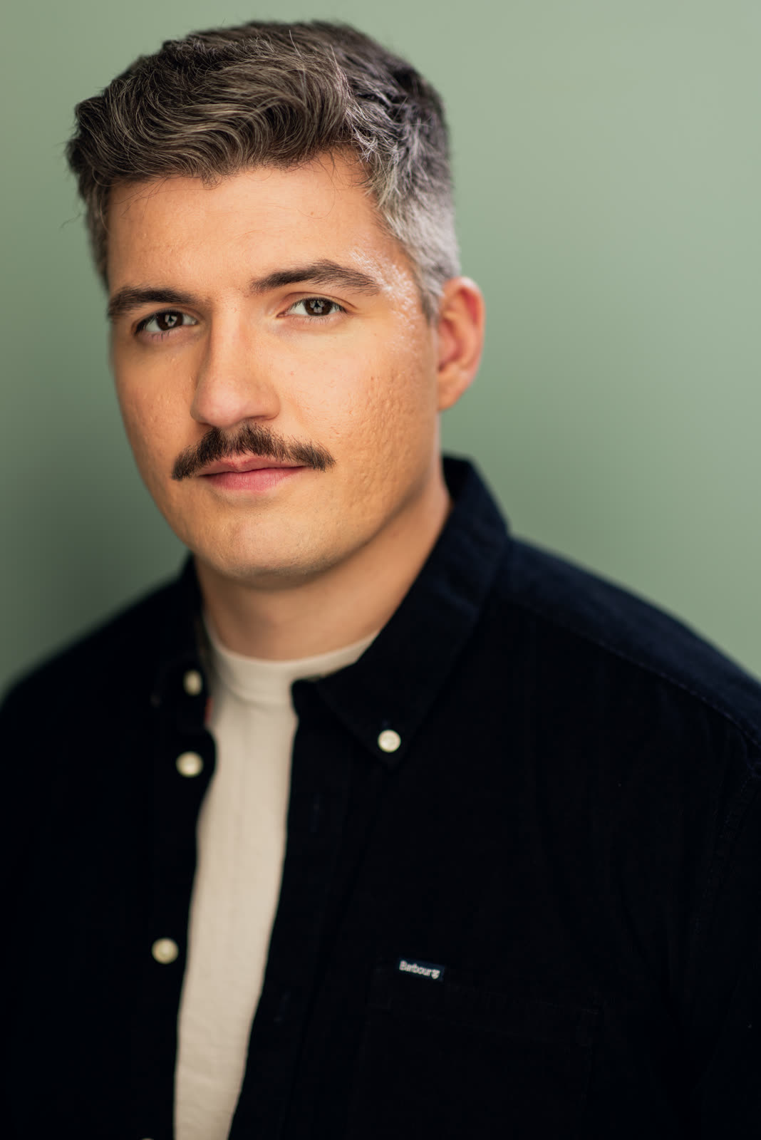 Eugene Romanchuk, commercial headshot: navy shirt against a sage green background